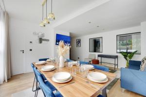 een eetkamer met een houten tafel en blauwe stoelen bij Chic 3-Bedroom Parisian Apartment in Vibrant Vincennes in Parijs
