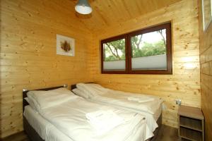 uma cama num chalé de madeira com uma janela em Eko-domki w Krynica Morska-Piaski em Nowa Karczma