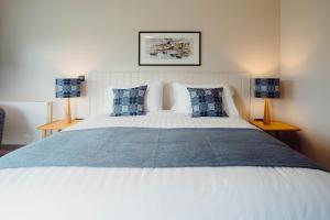 a bedroom with a large white bed with blue pillows at The Dunes in Tenby
