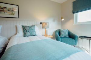 a bedroom with a bed and a blue chair at The Dunes in Tenby