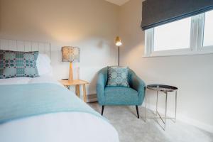 a bedroom with a bed and a chair and a window at The Dunes in Tenby