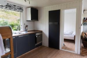 a kitchen with a sink and a door to a bedroom at Cottage with stunning view of the sea and islands. in Leynar