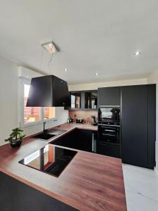 a kitchen with black appliances and a wooden counter top at Stylish rooftop avec terrasse à 2pas de Disney Paris in Montévrain