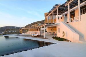 a house with a swimming pool next to a body of water at Luxurious Mykonos Villa 7 Bedrooms Villa Melianthe Private Infinity Pool and Astounding Sunset Sea Views Agios Ioannis in Dexamenes