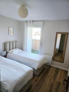 a bedroom with two beds and a mirror and a window at Stylish rooftop avec terrasse à 2pas de Disney Paris in Montévrain