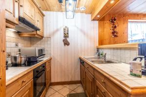 Una cocina con gabinetes de madera y encimera. en GRANGE 3, en Morzine