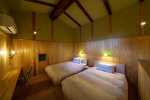 a room with two beds and a desk with lights at ゲストハウス小布施 in Obuse