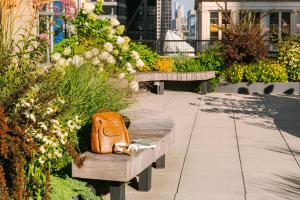 Eine orangefarbene Tasche steht auf einer Bank in einem Garten. in der Unterkunft 17John in New York