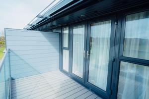 a balcony with glass doors on a house at The Dunes in Tenby