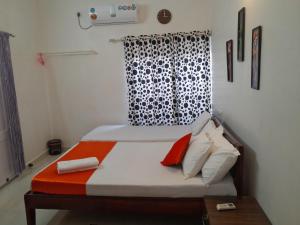 a bedroom with a bed with orange and white pillows at LA CASA THE HOMESTAY in Trivandrum