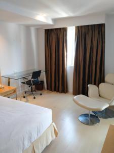um quarto de hotel com uma cama, uma secretária e cadeiras em The Tivoli Hotel em Banguecoque