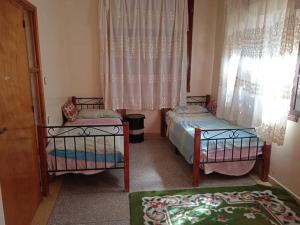- une chambre avec 2 lits et une fenêtre dans l'établissement Rez-de-chaussée villa touta, à Béni Mellal