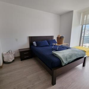 a bedroom with a bed with blue sheets and a window at Suite Martina 2 Personas Quito in Quito