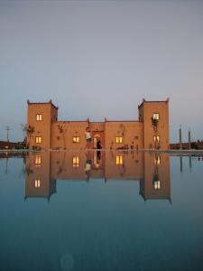 un edificio con su reflejo en el agua en Berber Palace Merzouga en Merzouga