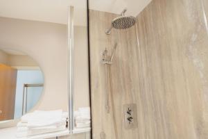 a shower in a bathroom with a mirror at The Dunes in Tenby