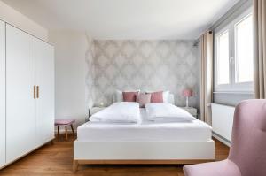 a white bedroom with a white bed with pink accents at PRIMERA Zimmer mit Gemeinschaftsbad in Singen