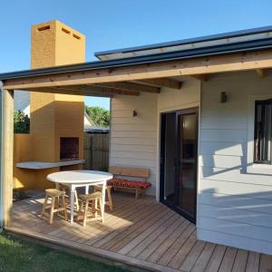 a patio with a table and chairs on a deck at Brand new cottage, walk to beach - inverter, wi-fi, DSTV in Cape St Francis