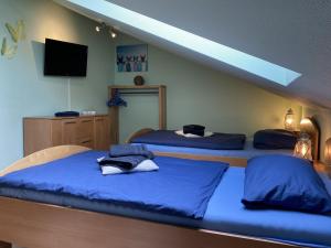 1 dormitorio con 2 camas con sábanas azules y TV en Haus Sansibar Niendorf, en Timmendorfer Strand