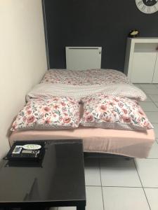 a bed with a blanket on it with a table at Appartement au calme proche centre ville in Quimper