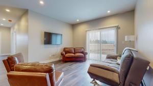 sala de estar con muebles de cuero y TV de pantalla plana en Scenic Mountain Views at Olympia Way-Unit A, en Kalispell