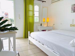 a bedroom with a white bed and a table and a window at Optasia Apartments in Hersonissos