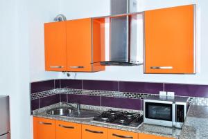 a kitchen with orange cabinets and a microwave at Appart Clim Wifi 700m de la Plage in Saïdia