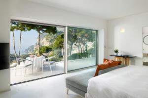 a bedroom with a large window and a table and chairs at Hotel Scalinatella in Capri +37 photos