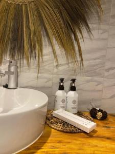 Baño con 2 botellas de jabón y lavamanos en FURAHA BEACH ROOMS en Kendwa
