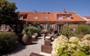 a house with a courtyard with chairs and plants at Hotel Hinrichs in Carolinensiel