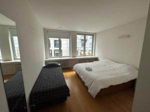 a small bedroom with a bed and two windows at 2 Bedroom Apartment in Lovely Louise Area in Brussels