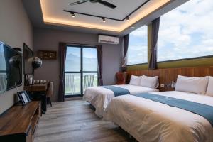 ein Hotelzimmer mit 2 Betten und einem großen Fenster in der Unterkunft 發現七星潭海景民宿 in Hualien