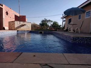einen Pool mit Sonnenschirm neben einem Haus in der Unterkunft Quarto Privativo em Santana de Parnaiba 02 in Santana de Parnaíba