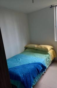 1 dormitorio con cama con sábanas azules y ventana en Apartamento hogareño, en Pereira