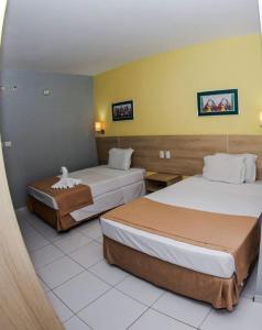 um quarto de hotel com duas camas e paredes amarelas em Gree Hotel em São Luís