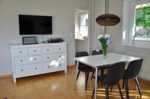 Apartment Aste في Aldrans: طاولة غرفة طعام بيضاء مع كراسي وخزانة بيضاء