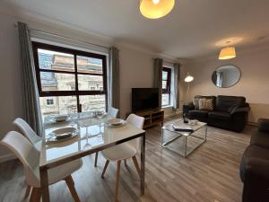 uma sala de estar com uma mesa e cadeiras e um sofá em Principal Apartments - Merchant City em Glasgow