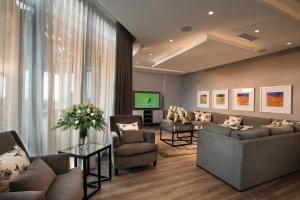 a living room with couches and chairs and a television at DAVINCI Suites in Johannesburg