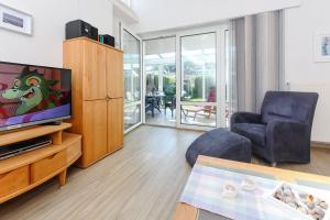 een woonkamer met een tv en een bank en een stoel bij Ferienhaus Engelke in Bensersiel
