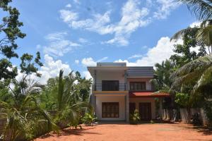 une maison avec des palmiers devant elle dans l'établissement Camellia Resort, à Anurâdhapura