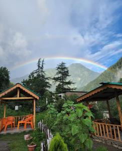 einen Regenbogen am Himmel über einem Garten in der Unterkunft Renuka homestay and cafe in Kasol