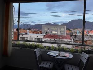 uma vista para a cidade a partir de uma janela com uma mesa e cadeiras em Apartamento movistar Arena-Estadio El Campin-galerías con garaje 2 a 6 personas em Bogotá