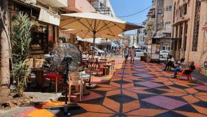 a sidewalk with an umbrella and tables and chairs at Bauhaus Studio - Sun Balcony - Rothschild Boulevard in Tel Aviv