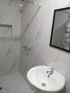 a white bathroom with a sink and a mirror at Apartamentos Cristo Rey. in Tacna