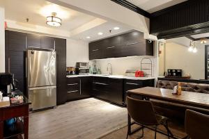 a kitchen with black cabinets and a stainless steel refrigerator at Independence Square 207, Chic Studio in Downtown Aspen, 1 Block from Gondola in Aspen