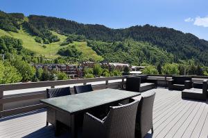 une table et des chaises sur une terrasse avec une montagne dans l'établissement Independence Square 207, Chic Studio in Downtown Aspen, 1 Block from Gondola, à Aspen