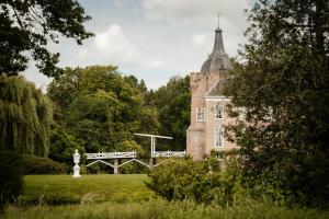 un ancien bâtiment avec une tour au-dessus d'un champ dans l'établissement Heeren van Acquoy, à Acquoy