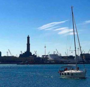 een boot in het water met een vuurtoren op de achtergrond bij CASA AZZURRA, nel cuore di Genova in Genua