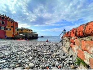 een persoon die op een rotsachtig strand naast de oceaan staat bij CASA AZZURRA, nel cuore di Genova in Genua