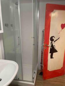 een badkamer met een rode deur met een schilderij van een vrouw bij CASA AZZURRA, nel cuore di Genova in Genua