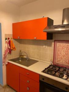 een keuken met oranje kasten, een wastafel en een fornuis bij CASA AZZURRA, nel cuore di Genova in Genua